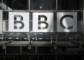 A photograph taken on October 6, 2022 shows the BBC logo at the entrance of the BBC headquarters at Broadcasting House in central London. - On November 14, 1922, the clipped tones of the BBC's director of programmes, Arthur Burrows, crackled across the airwaves. "This is 2LO, Marconi House, London calling," he announced and with that, public service broadcasting in Britain was born. One hundred years on, the British Broadcasting Corporation is a global media giant. But its centenary comes at a time of drastic budget cuts that have raised questions about its future. (Photo by Justin TALLIS / AFP)