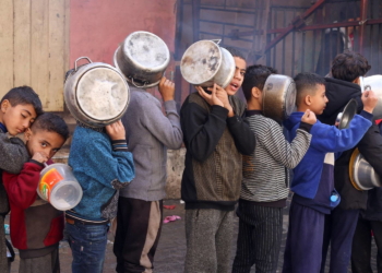 Palestinian children carry pots as they queue to receive food cooked by a charity kitchen, amid shortages in food supplies, as the conflict between Israel and Hamas continues, in Rafah in the southern Gaza Strip December 14, 2023. REUTERS/Saleh Salem     TPX IMAGES OF THE DAY
