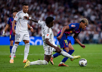 Lamine Yamal of FC Barcelona is in action with the ball, defended by Vinicius Junior of Real Madrid, during the LaLiga EA Sports football match between Real Madrid CF and FC Barcelona at Estadio Santiago Bernabeu in Madrid, Spain, on October 26, 2025. (Photo by Alberto Gardin/NurPhoto via Getty Images)